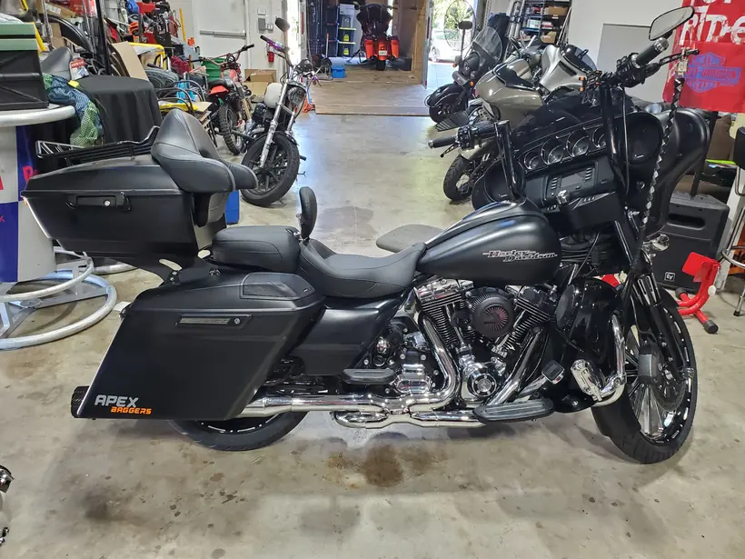 Matte black Harley bagger with an APEX Baggers decal inside the shop