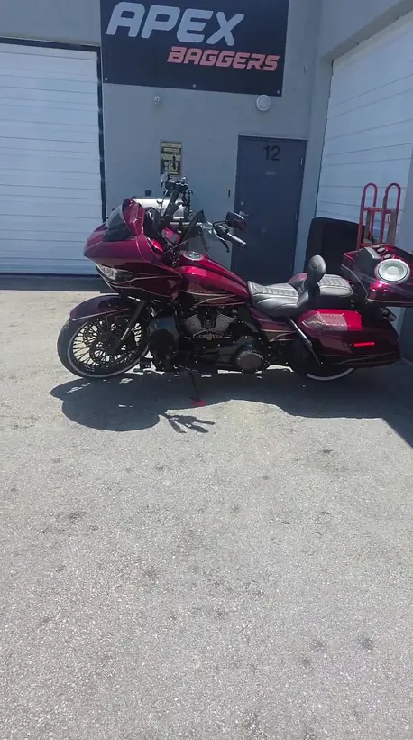 Red Harley Road Glide with rear speakers parked outside APEX Baggers