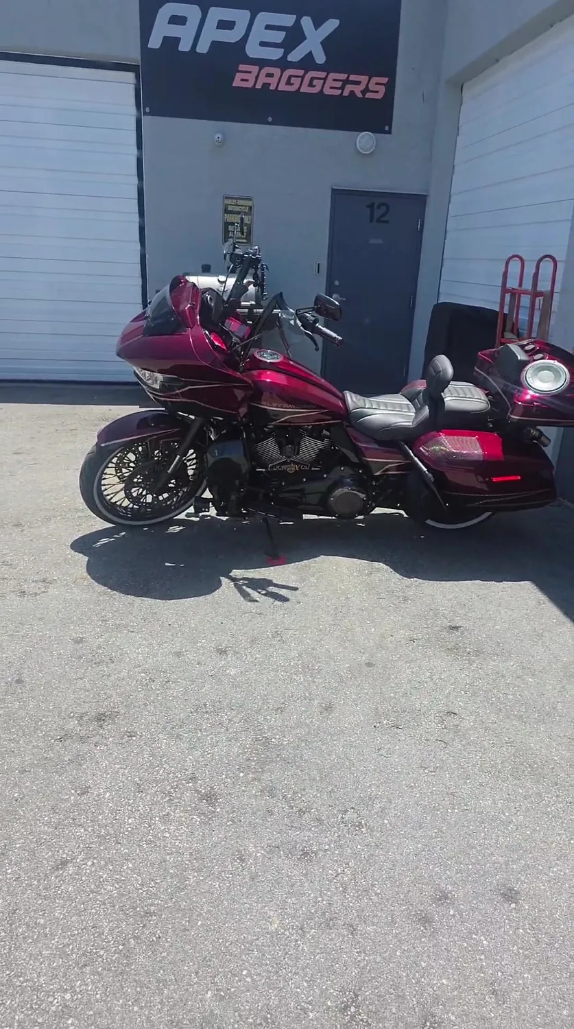 Red Harley Road Glide with a full audio system parked under the APEX Baggers sign