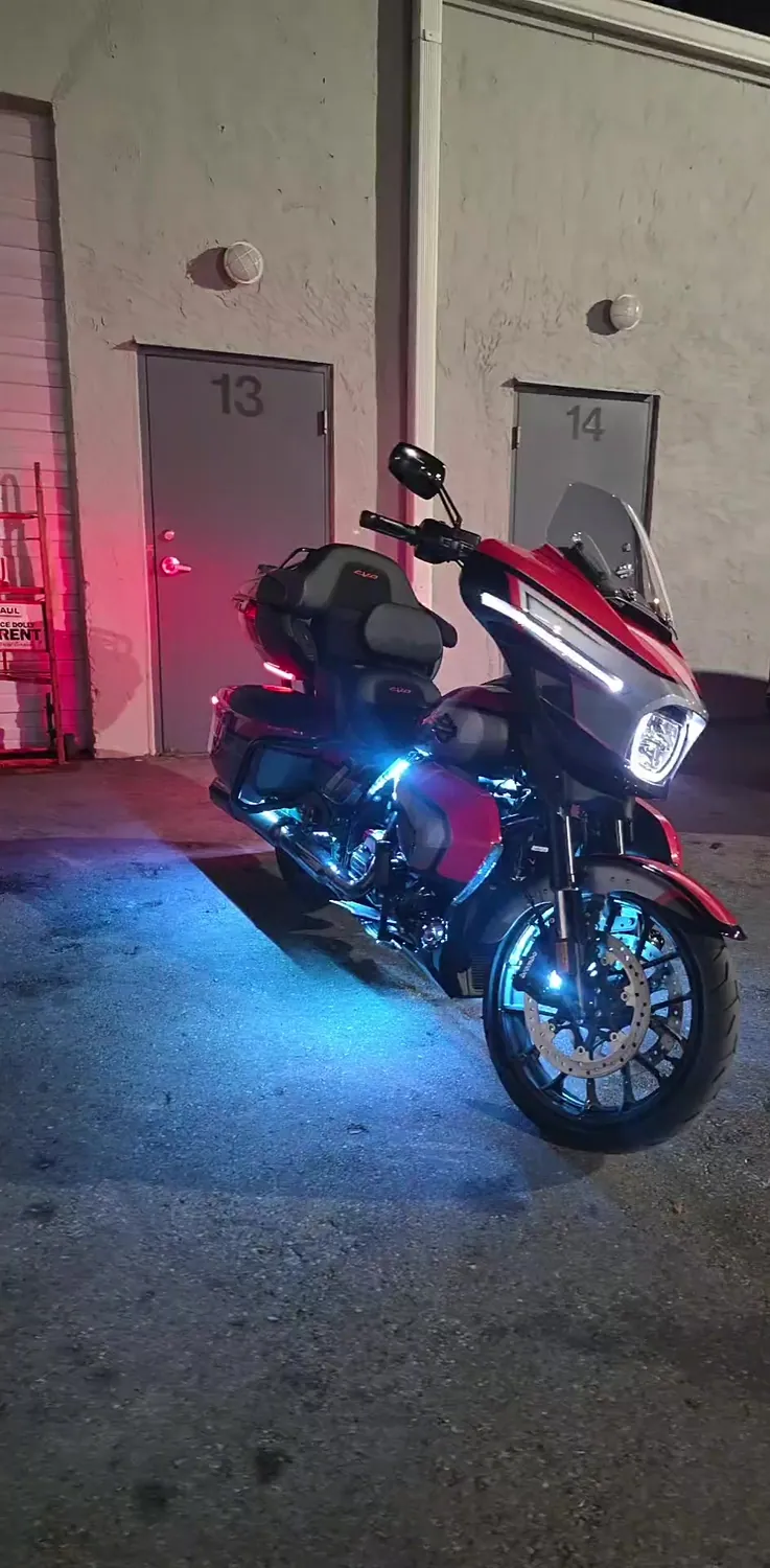 Harley Road Glide with blue underglow parked outside the APEX Baggers shop at night