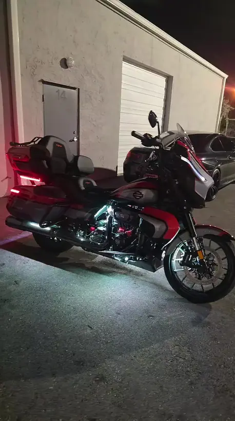 Harley Road Glide with underglow and red accent lighting outside the shop at night
