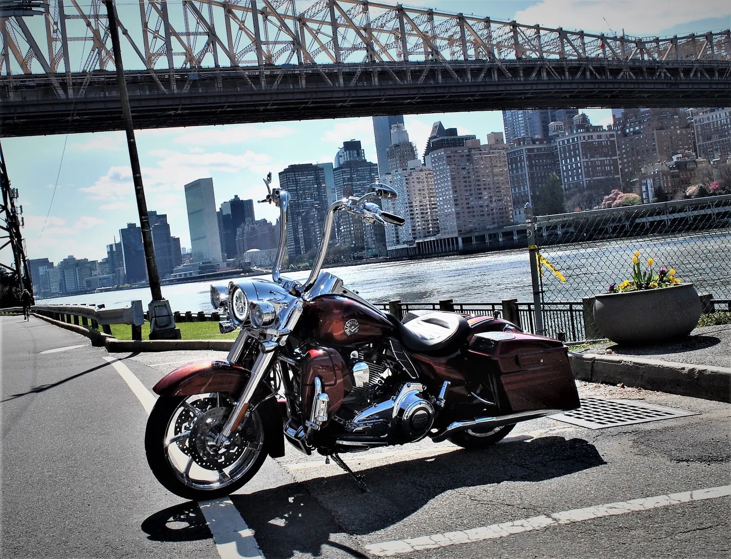Red 2013 CVO Road King with ape hangers parked under a bridge with a city skyline behind it
