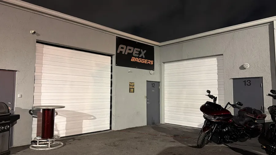 APEX Baggers shop front at night with a Road Glide parked outside