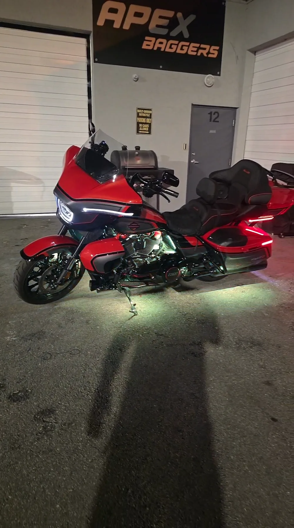 Red and black Harley Road Glide under the APEX Baggers sign at night